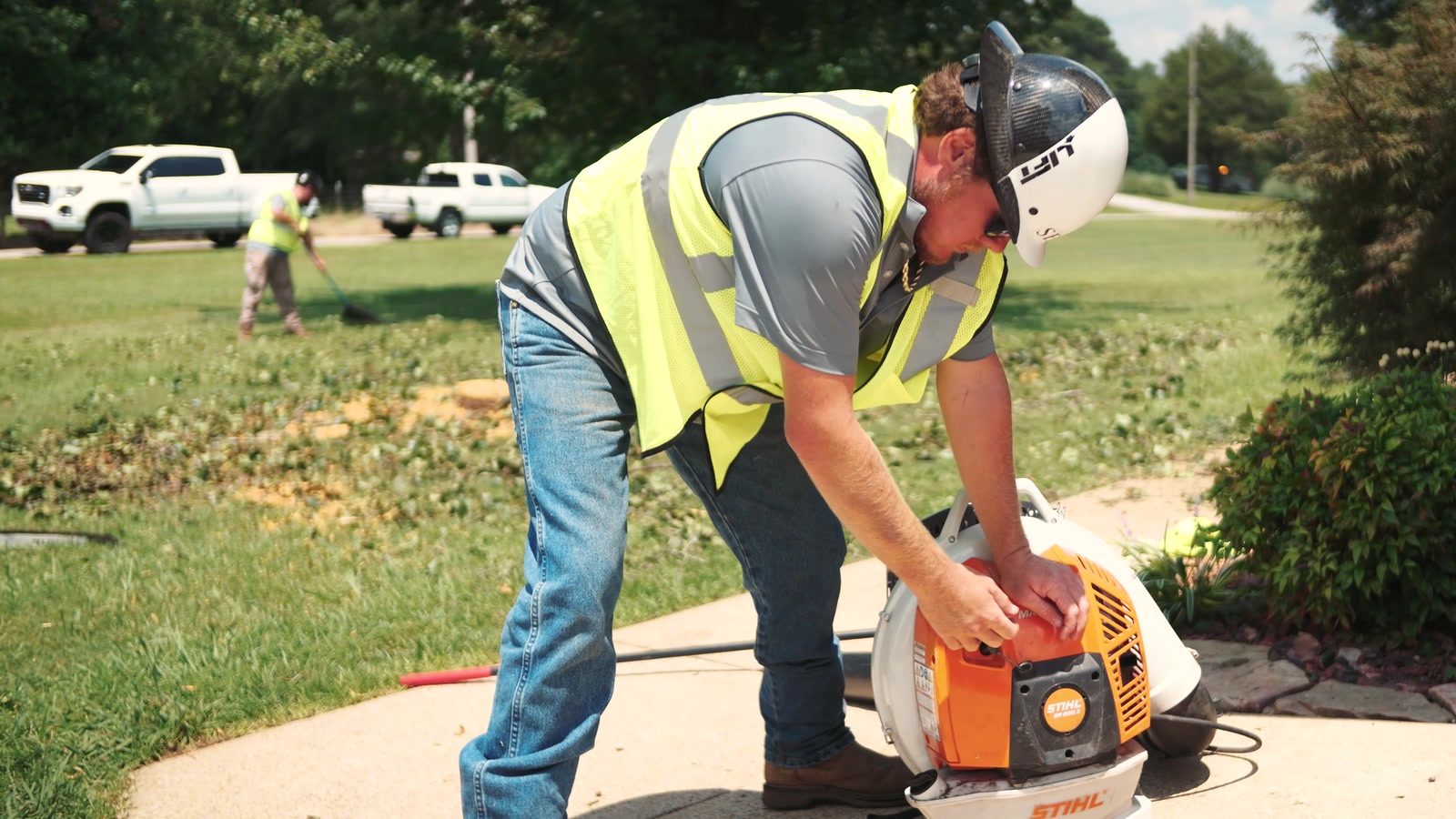 Crew member clearing a driveway with a blower after a residential tree job